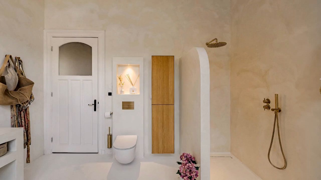 Badkamer met natuurstenen wanden en messing kranen